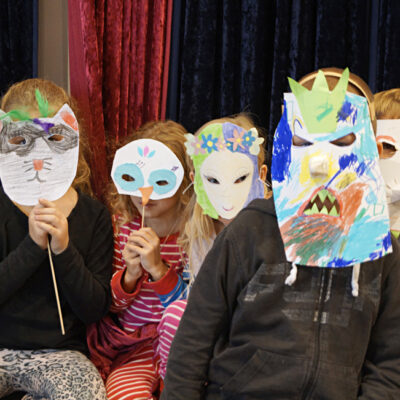 Fem barn står med sina färgglada masker framför ansiktet.