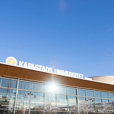 Karlstads universitetsbibliotek med solreflex i fönstren och blå himmel.