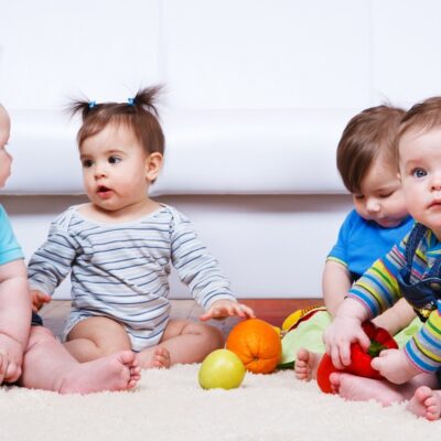 Fyra småbarn leker på golvet