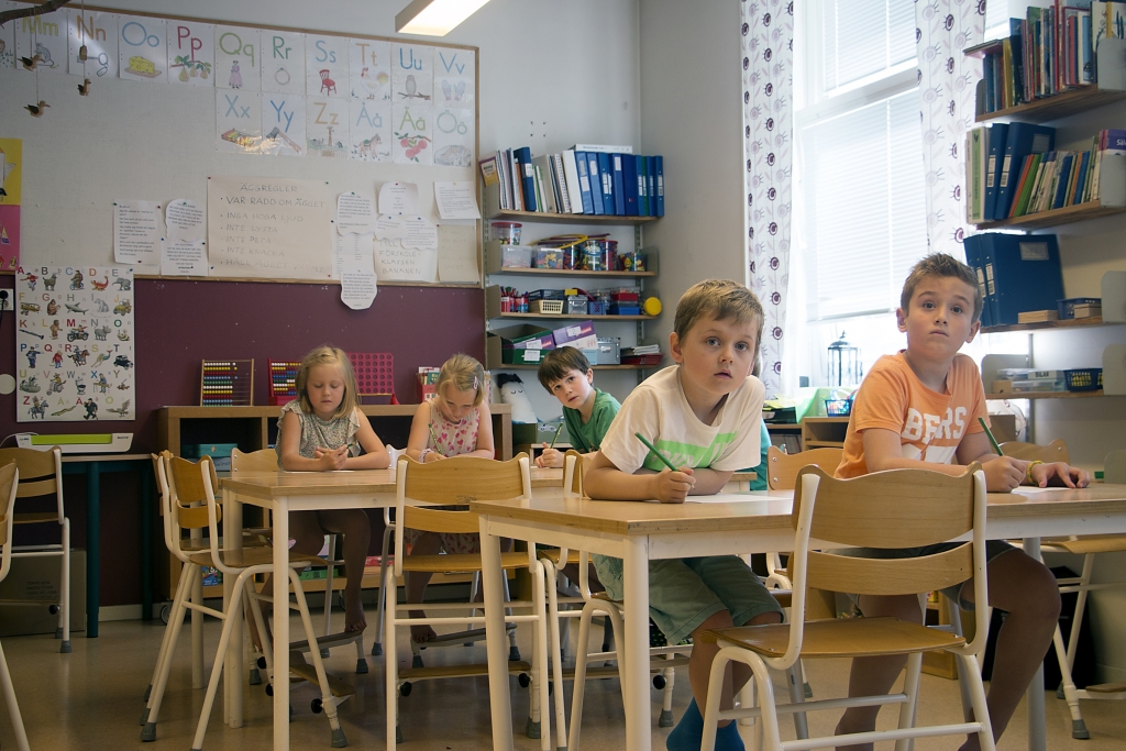 Fem barn sitter vid sina bänkar.