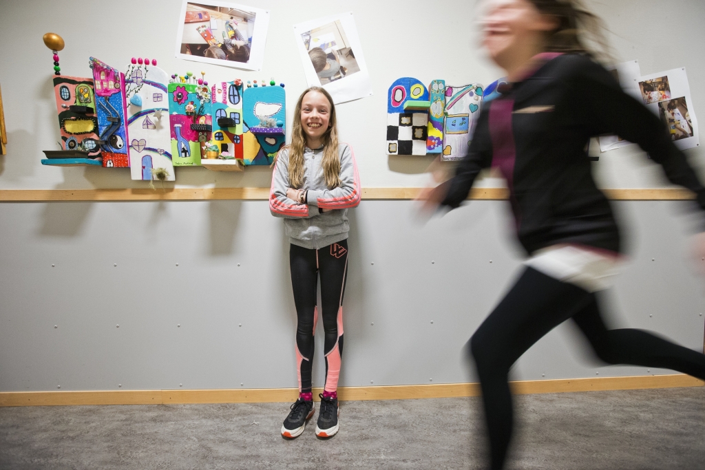 En elev står framför konstverket i korridoren och en annan elev springer förbi.