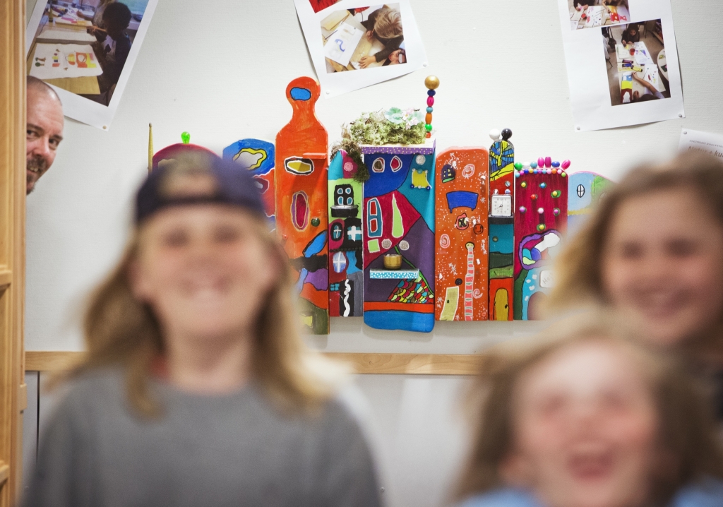 Tre elever i förgrunden och konstnären tittar fram i bakgrunden vid konstverket.