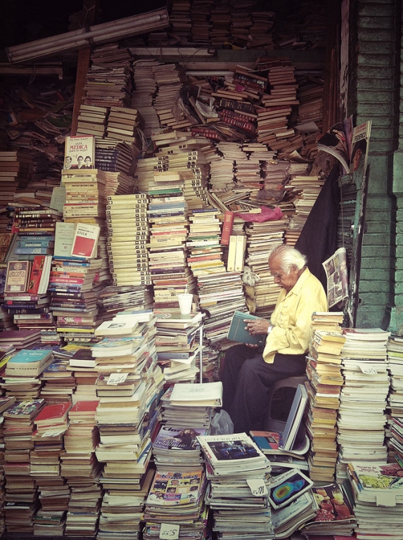 En man läser bland staplar av böcker