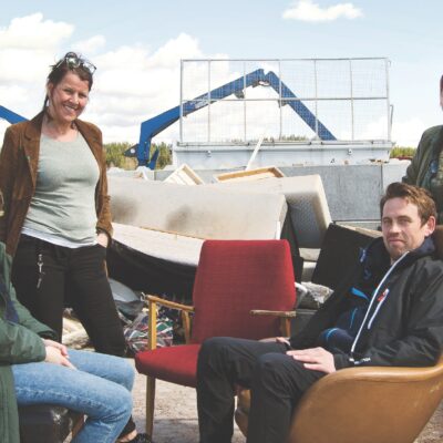 En konstnär och tre lärare framför skrot på återvinningsstation