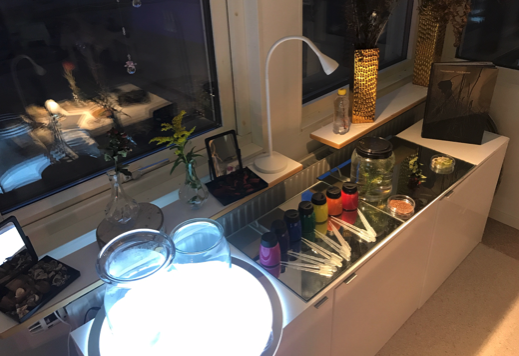 En ljusbänk och en arbetsbänk med små färgburkar och glasburkar.
