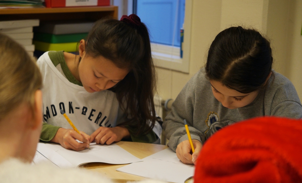 Två elever vid ett runt bord skriver.