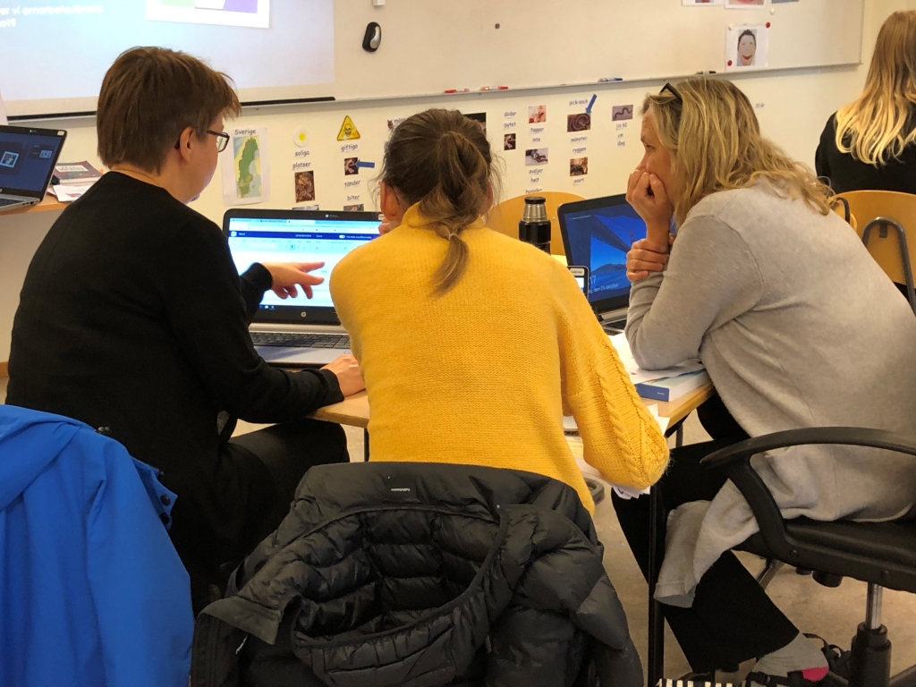 Tre lärare arbetar tillsammans framför datorer och en pekar på skärmen.