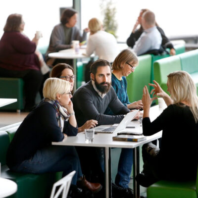 Vuxna studenter runt ett bord med gröna soffor