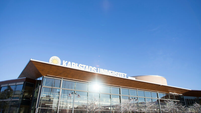 Karlstads universitetsbibliotek med solreflex i fönstren och blå himmel.